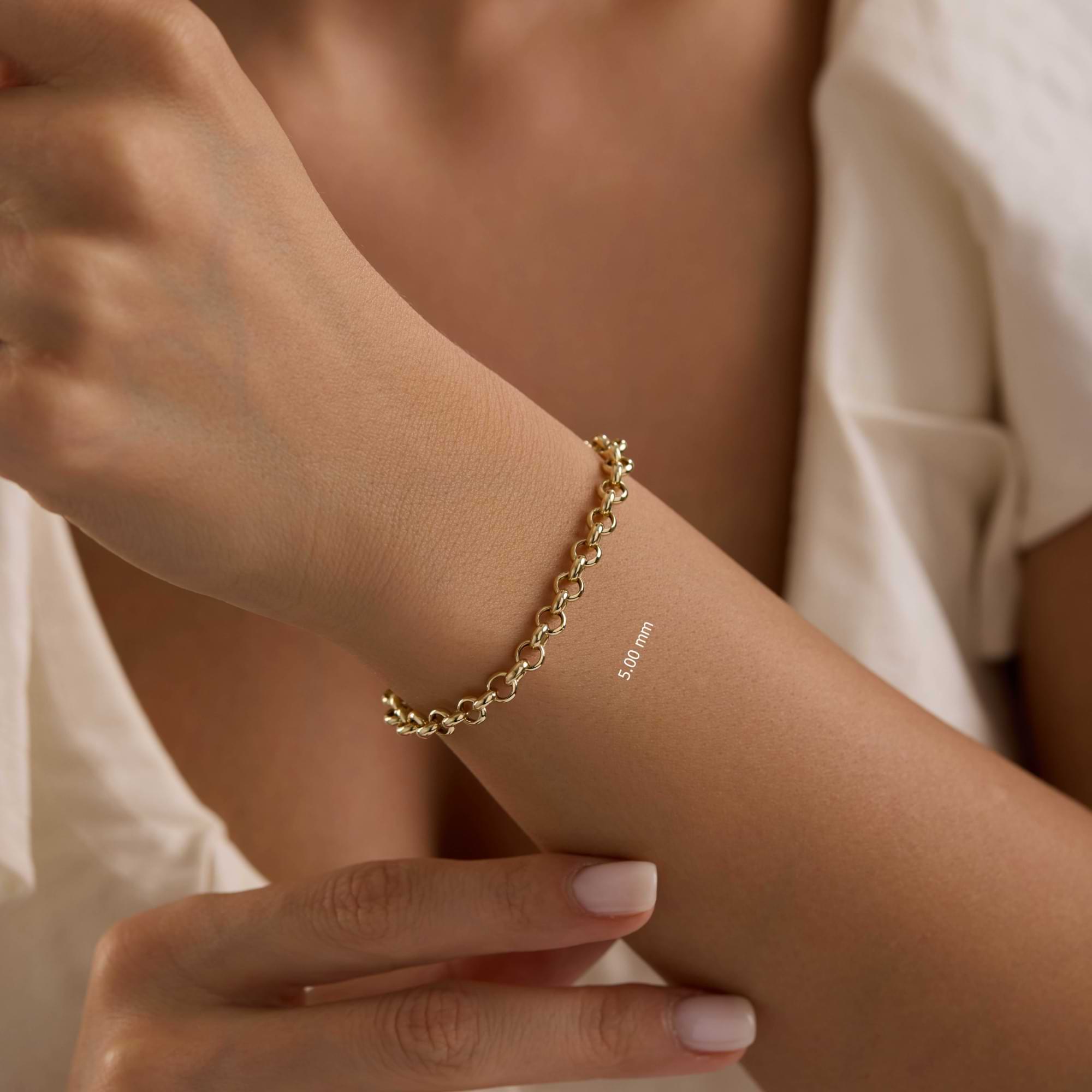 Gold5mm rolo chain bracelet on a wrist with a blurred background