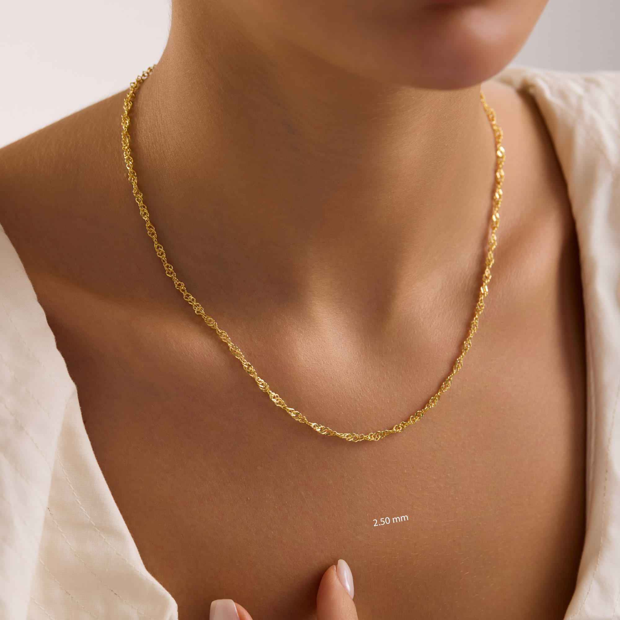 Gold 2.5mm singapore chain necklace on a person's neck with a neutral background