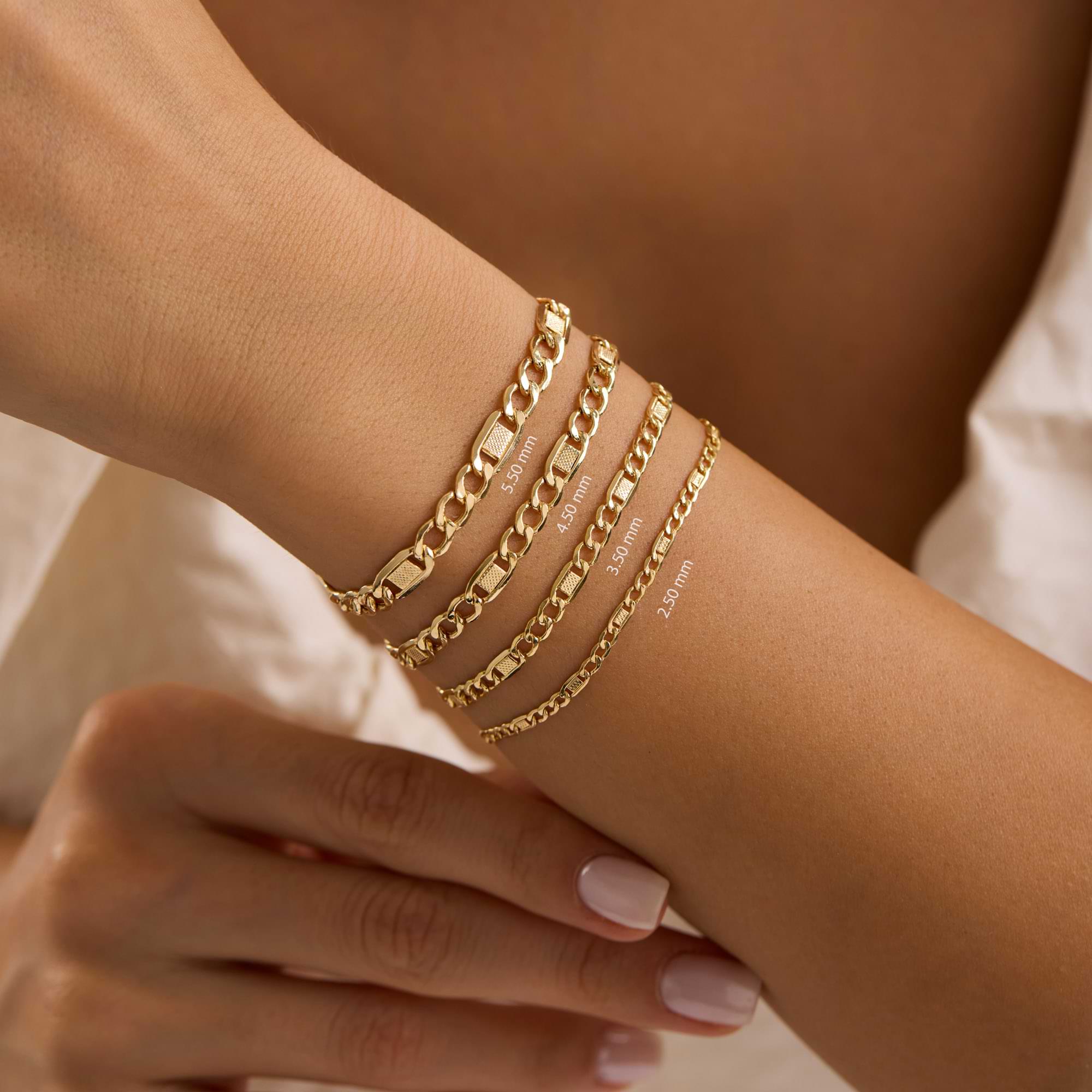 Gold textured figaro chain bracelets on a wrist of a woman