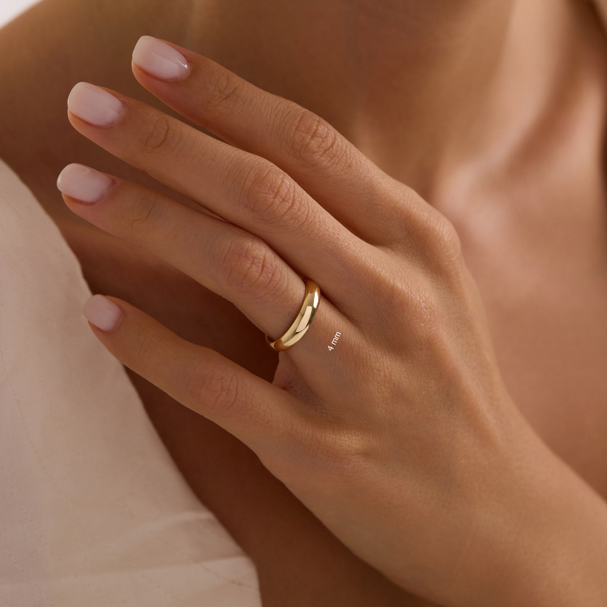 Close-up of hand wearing 4mm 14k yellow gold dome wedding band