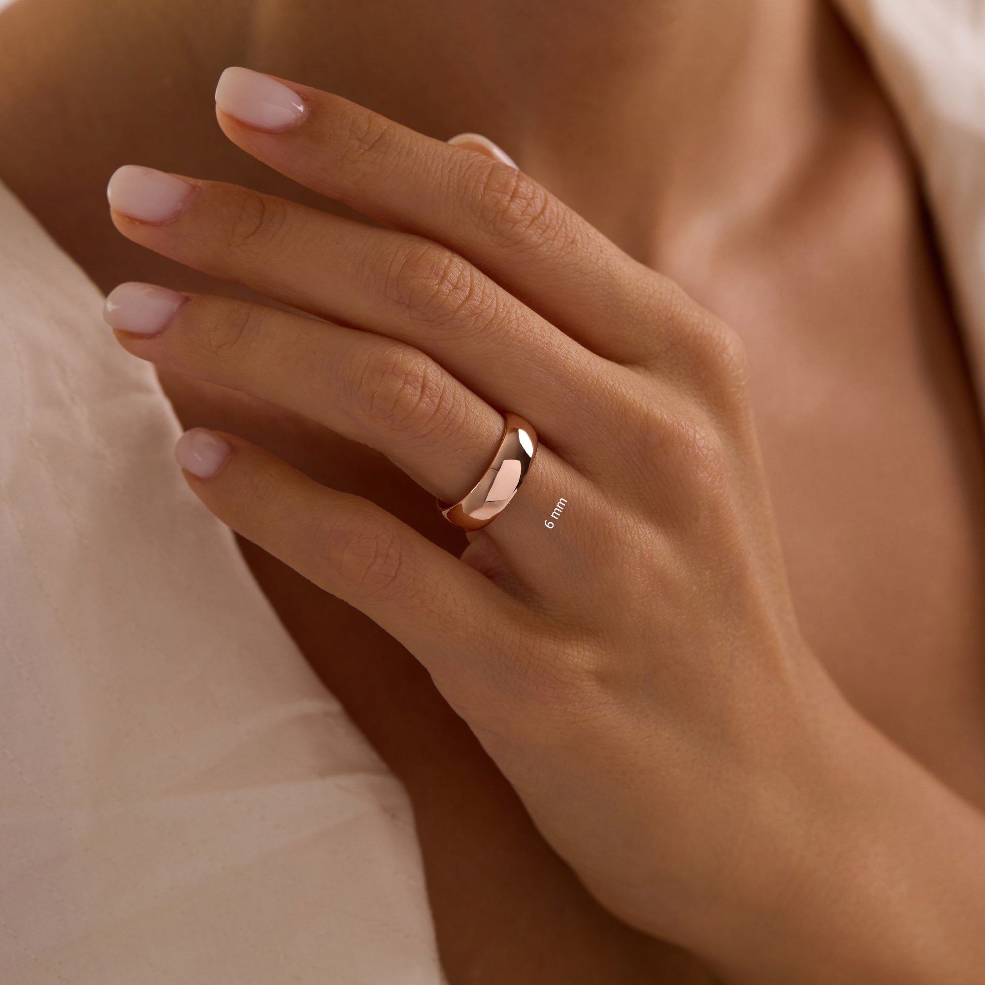 14k solid rose gold 6mm wedding band on woman’s hand, wide polished dome ring.
