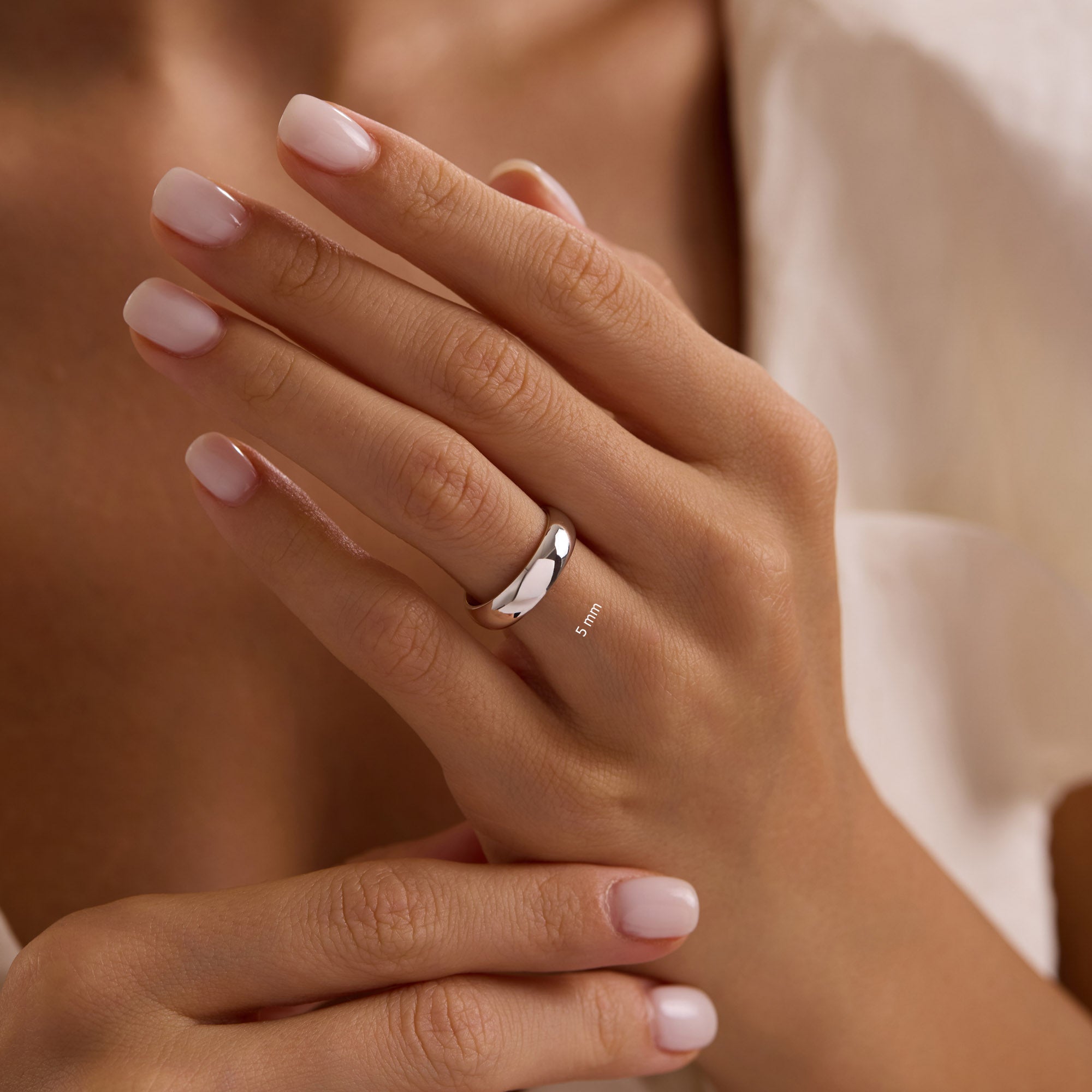 14k solid white gold 5mm wedding band on woman’s hand, classic polished dome ring.