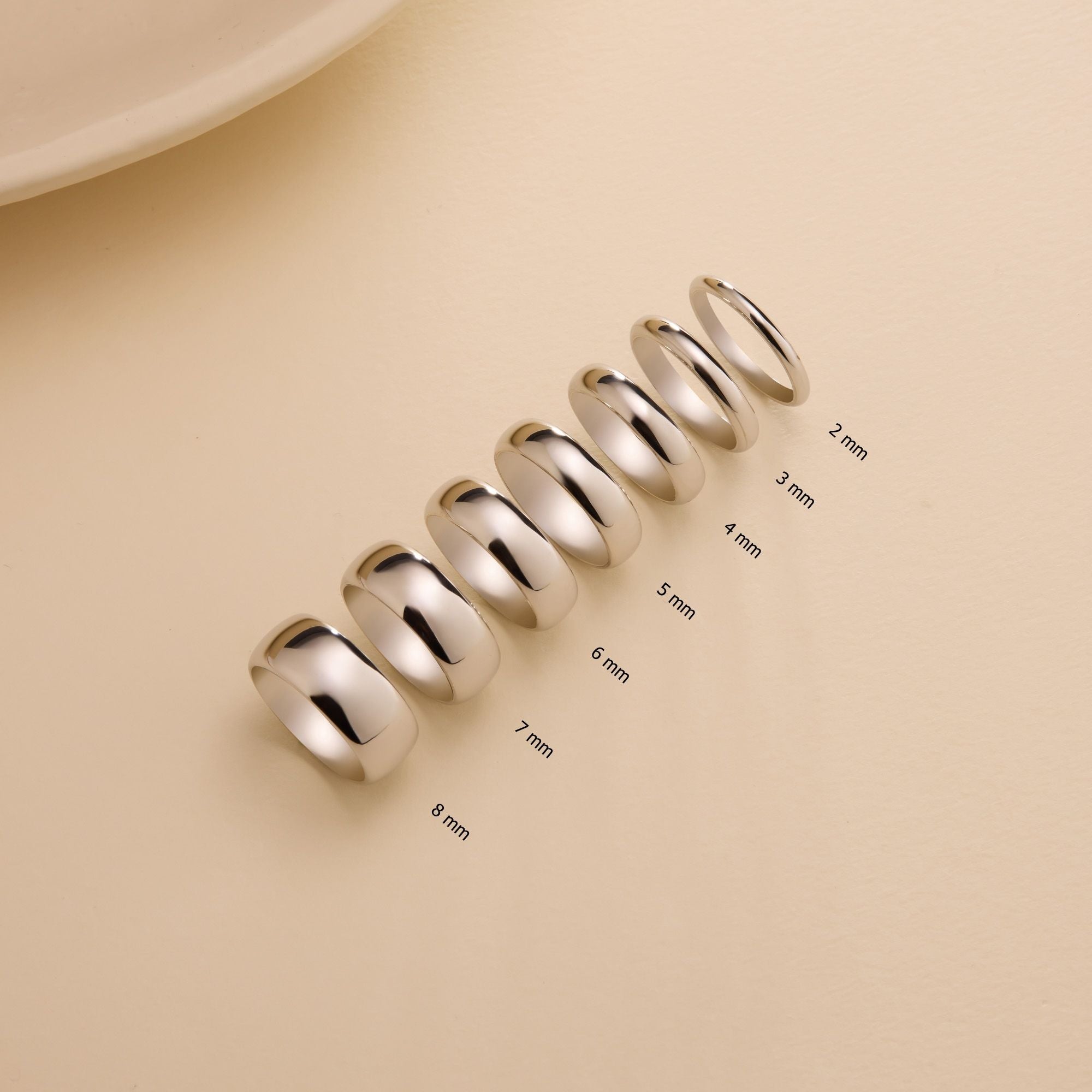 Row of 14k solid white gold dome wedding bands in widths 2mm, 3mm, 4mm, 5mm, 6mm, 7mm, and 8mm on neutral background.