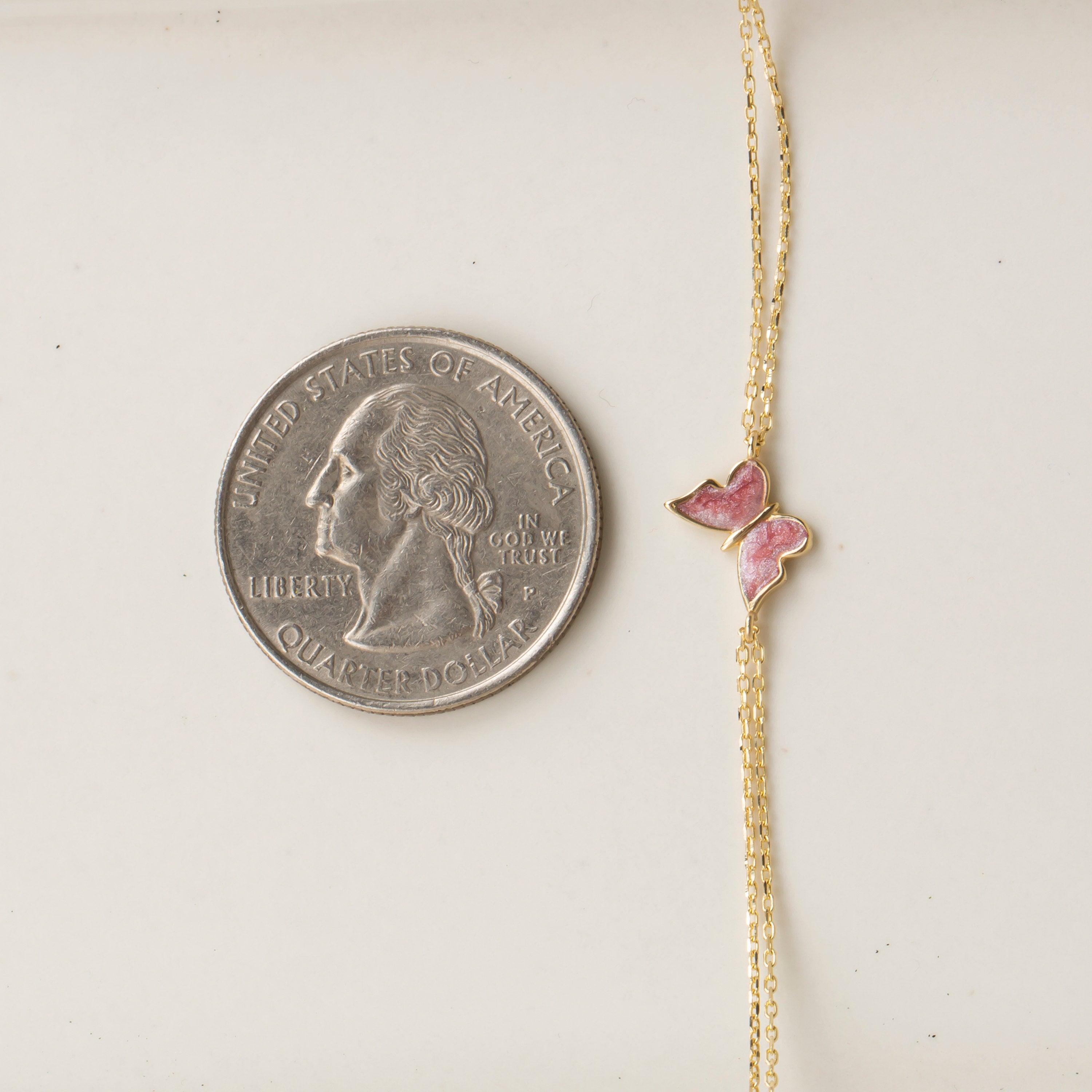 14k gold double chain bracelet with pink enamel butterfly charm shown next to US quarter for size reference