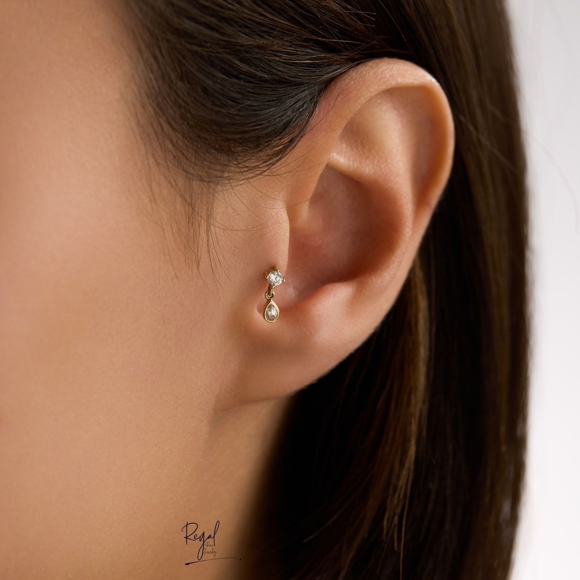 Close-up of woman's an ear tragus wearing a teardrop piercing 