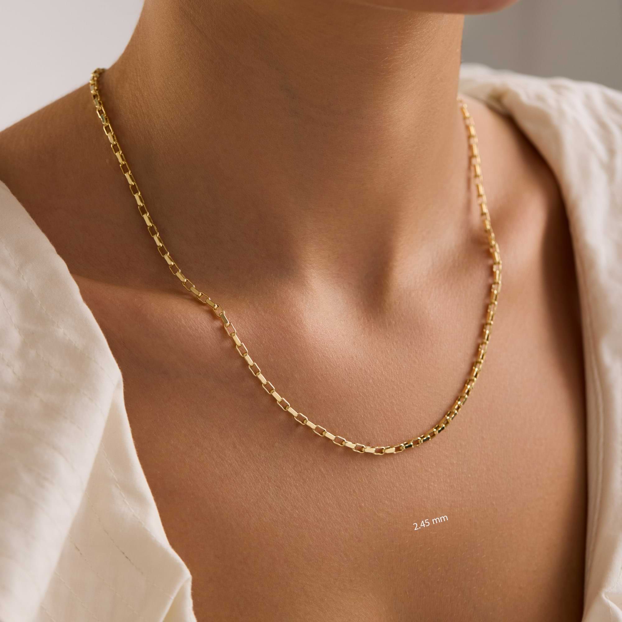 Gold 2.45mm cable chain necklace on a woman's neck with a neutral background 