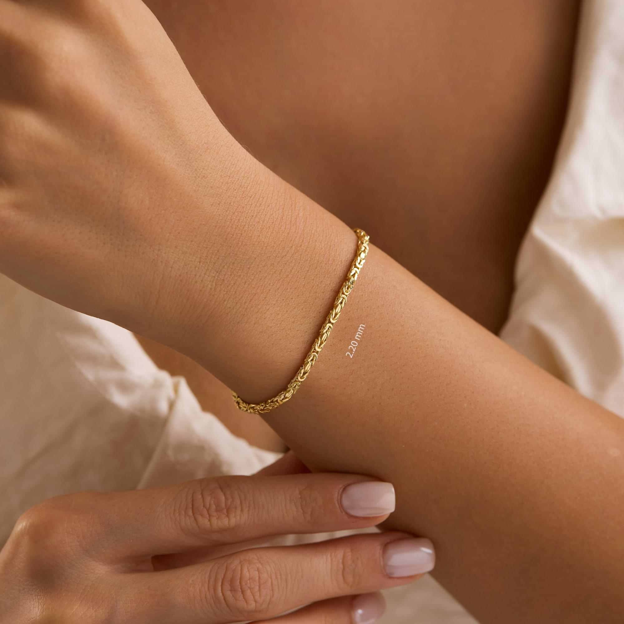 Gold  2.2mm byzantine chain bracelet on a wrist of woman wearing white dress