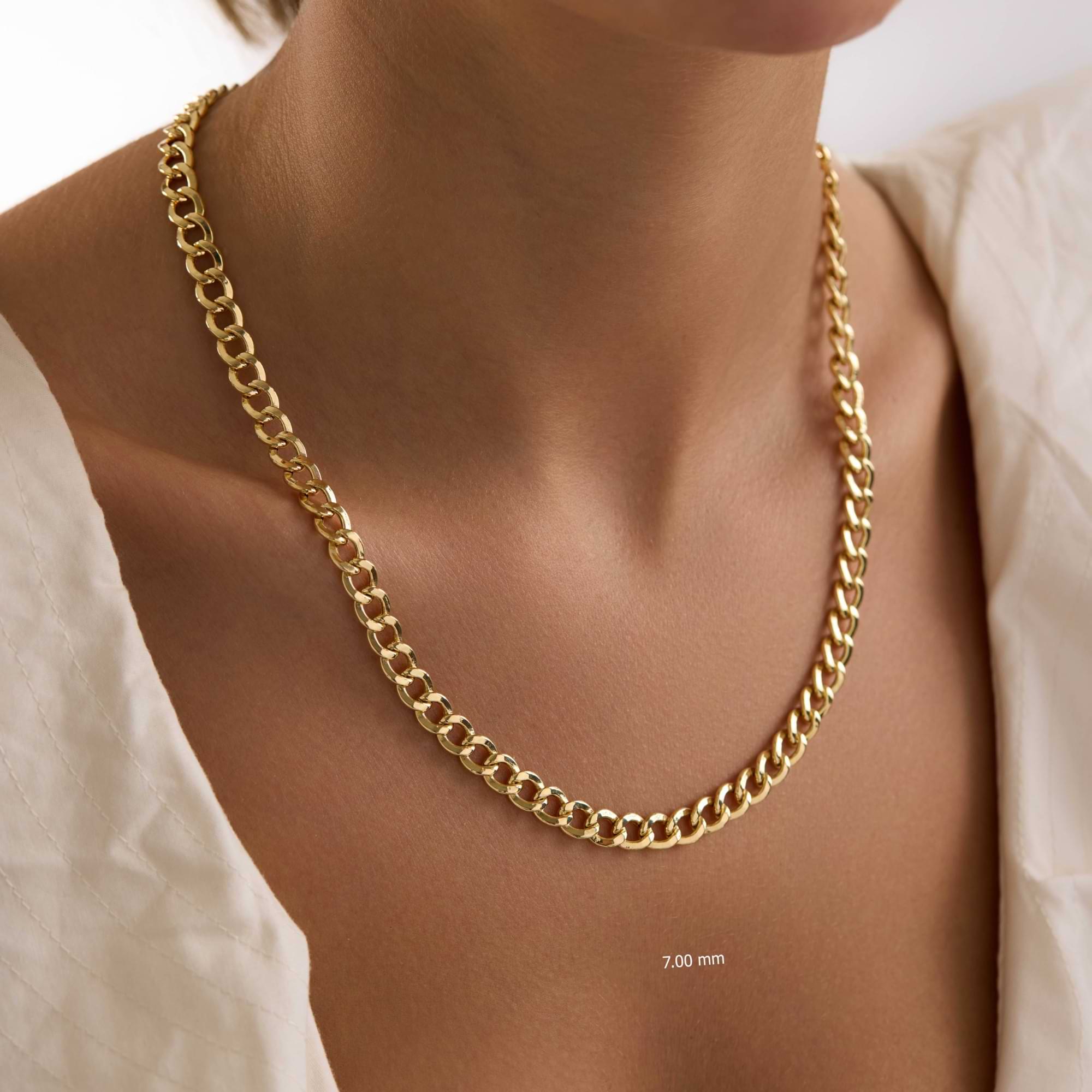 Gold 7mm Curb chain necklace on a woman's neck with a plain background