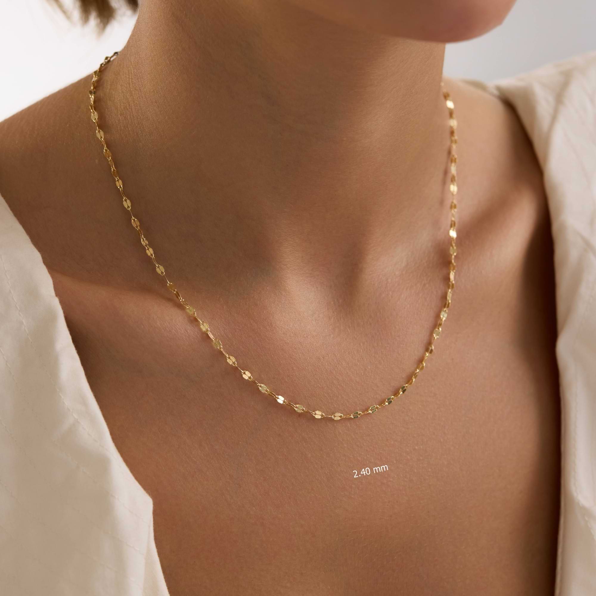 14k Gold sequin necklace on a person's neck with a plain background