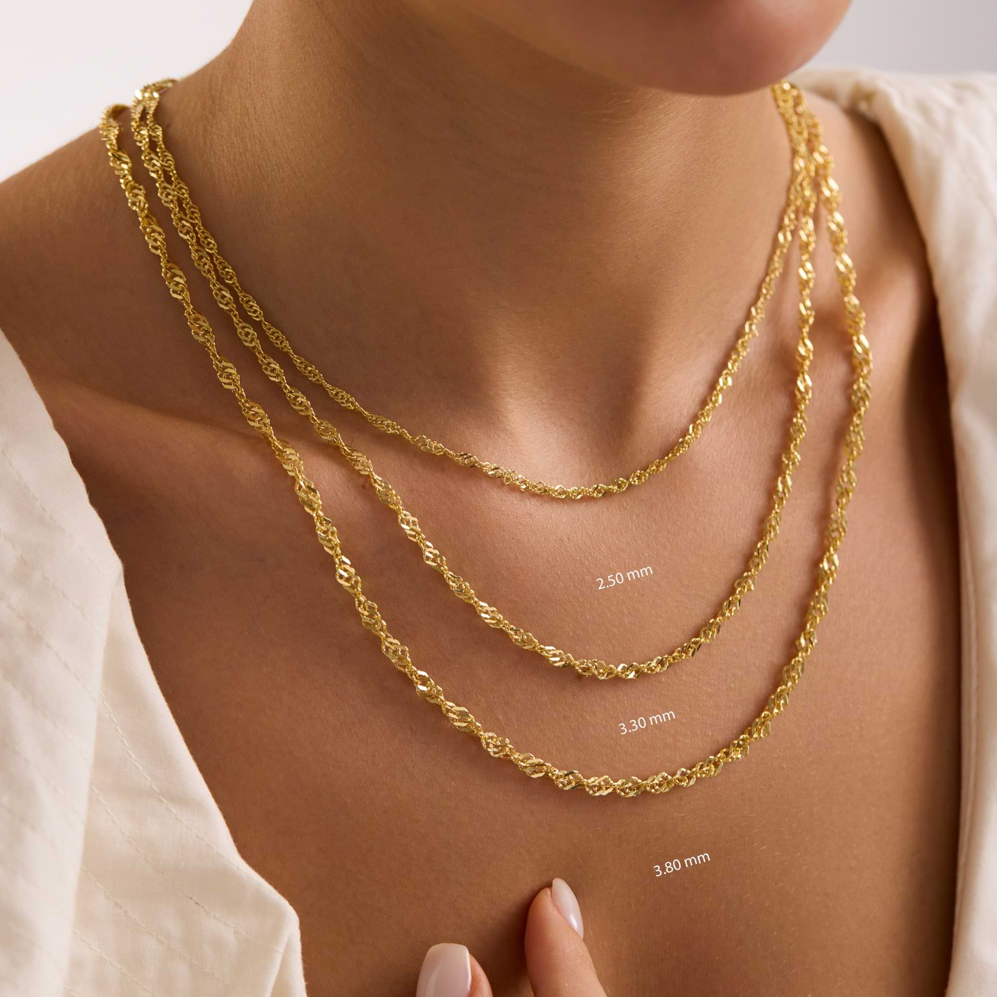 Three gold chains of different thicknesses displayed on a person's neck.