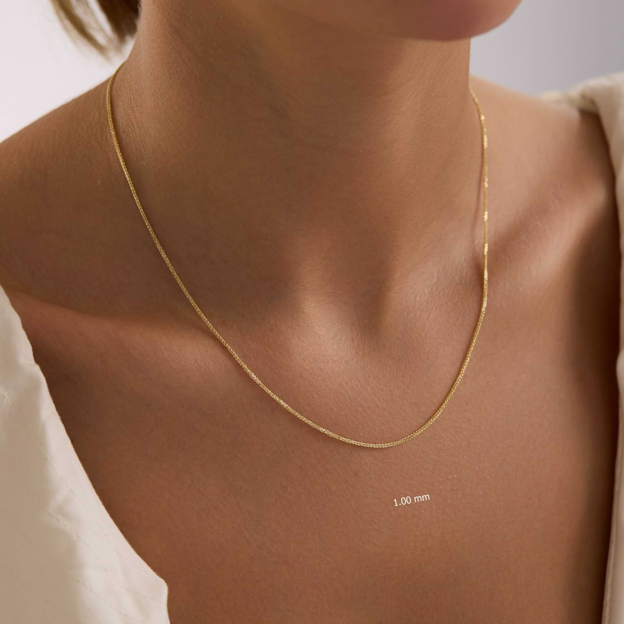 14k Gold 1mm spiga necklace on a person's neck with a plain background
