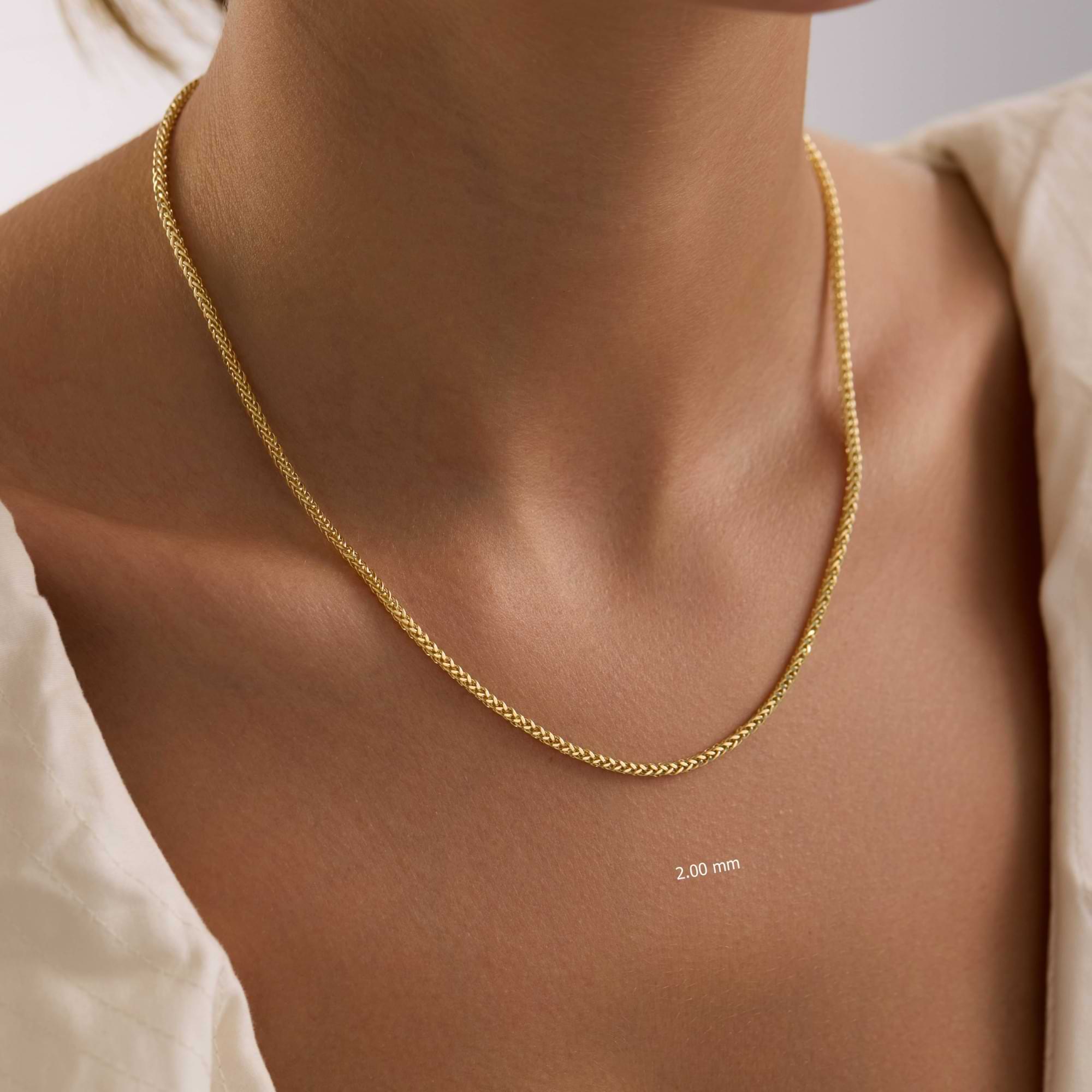 Gold 2mm spiga chain necklace on a lady with a plain background