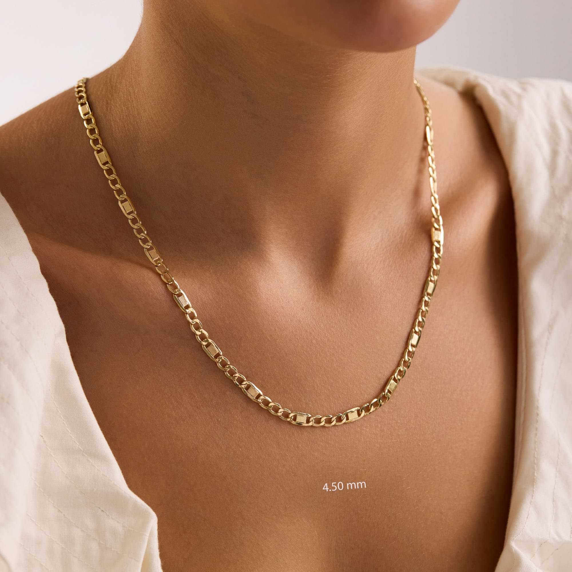 14k Gold 4.5mm textured figaro chain necklace on a woman with a plain background