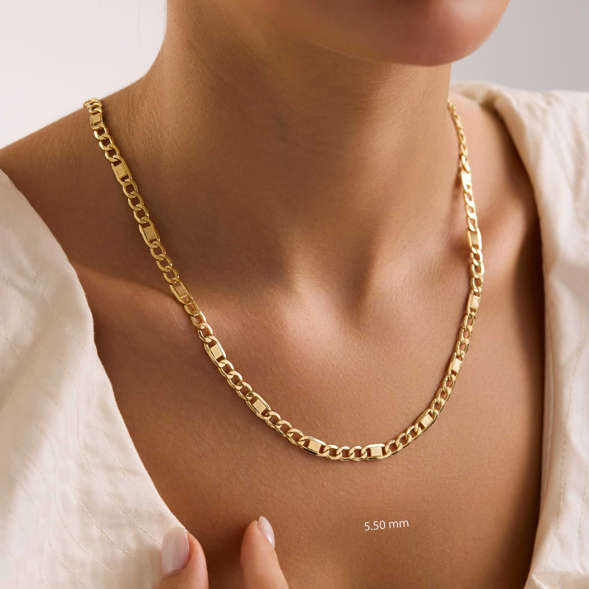 Gold 5.5mm textured figaro chain necklace on a woman with a neutral background