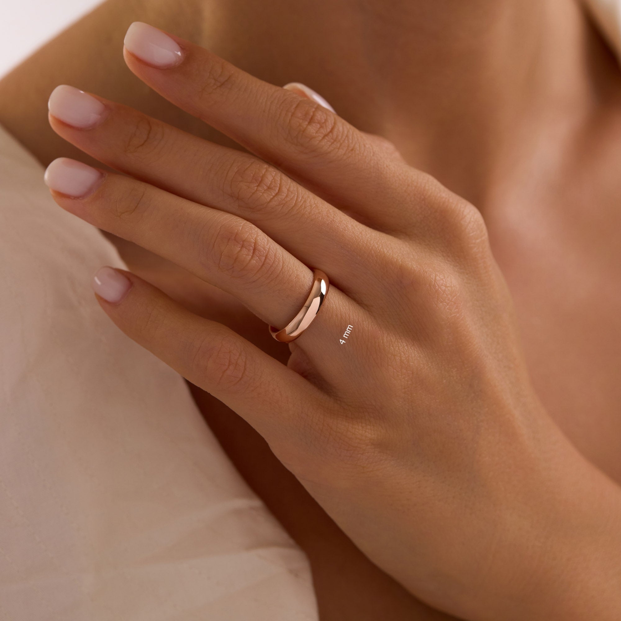 Close-up of hand wearing 4mm 14k rose gold dome wedding band