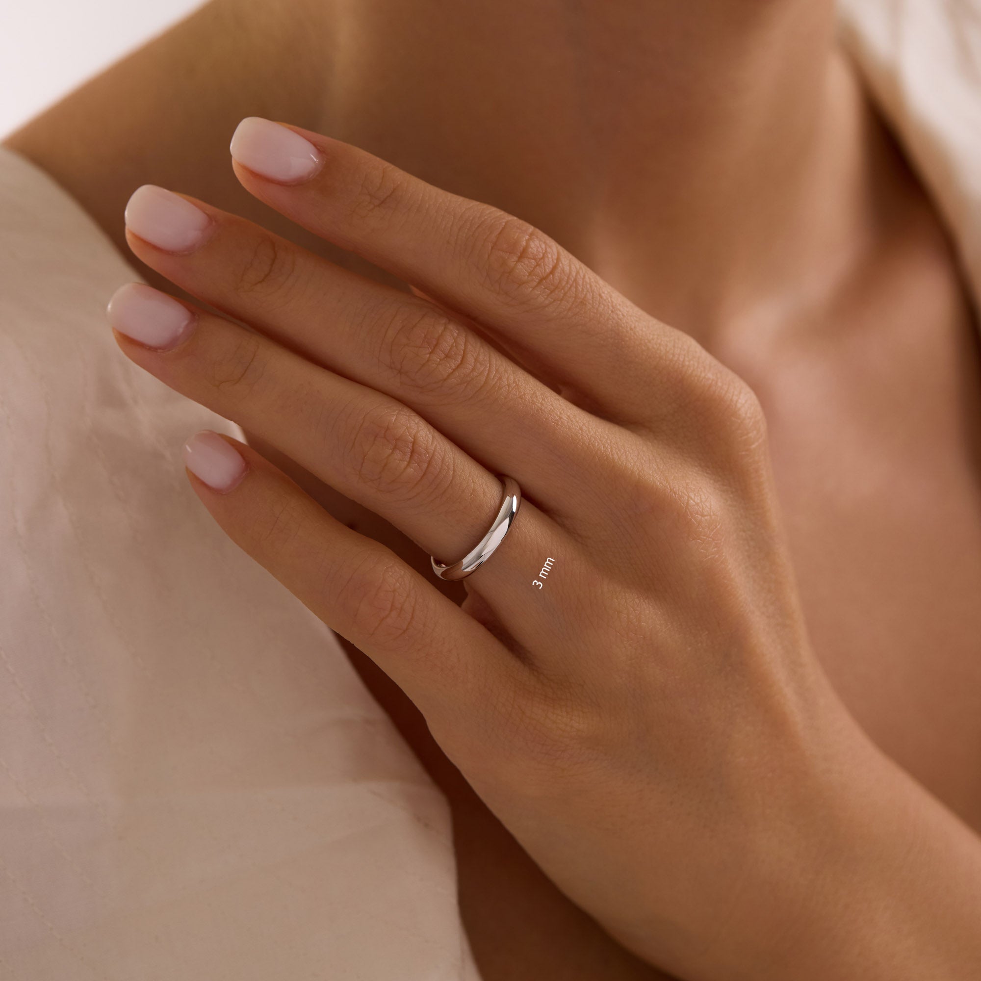 Close-up of hand wearing 3mm 14k white gold dome wedding band.