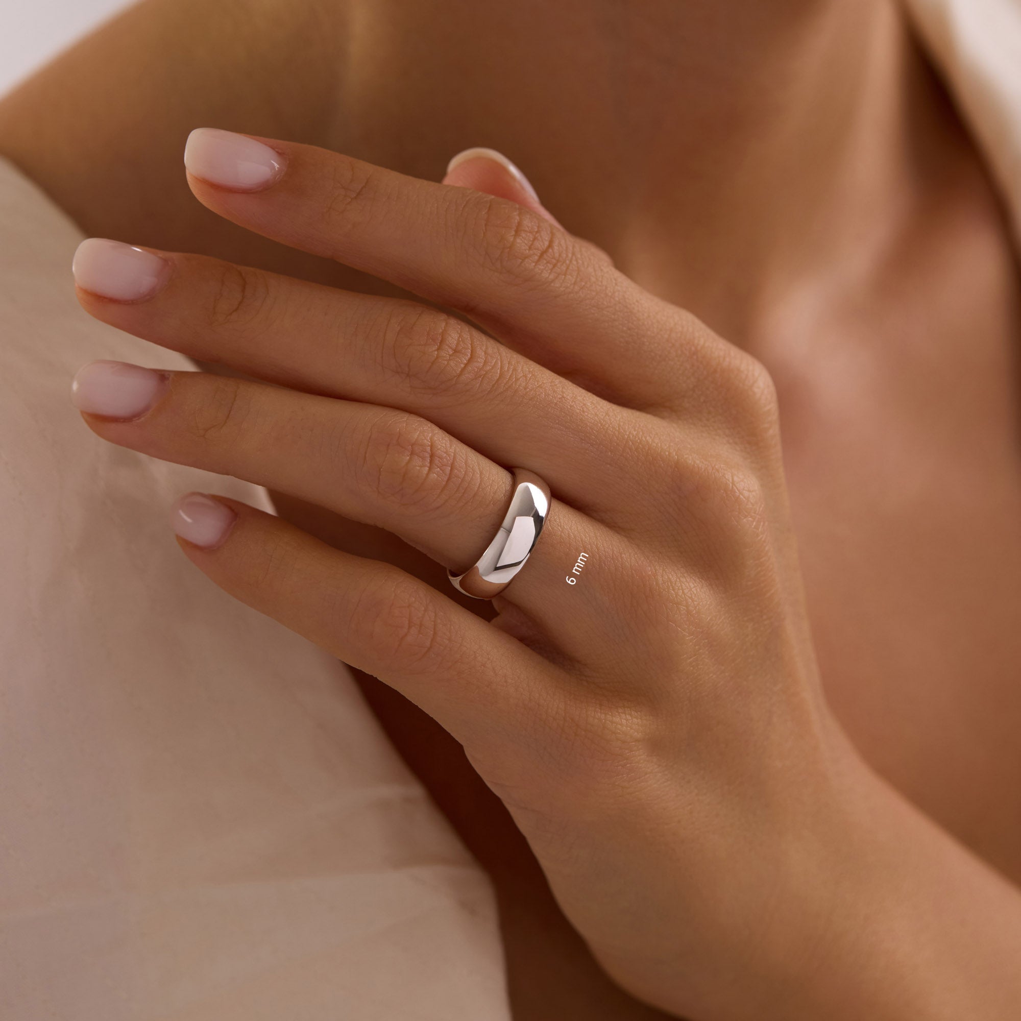 14k solid white gold 6mm wedding band on woman’s hand, wide polished dome ring.